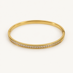 Gold-tone bangle on an ivory background