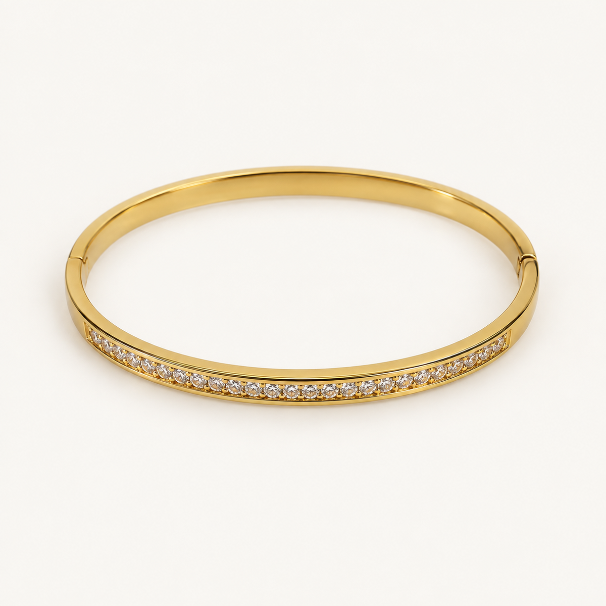 Gold-tone bangle on an ivory background