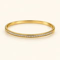 Gold-tone bangle on an ivory background